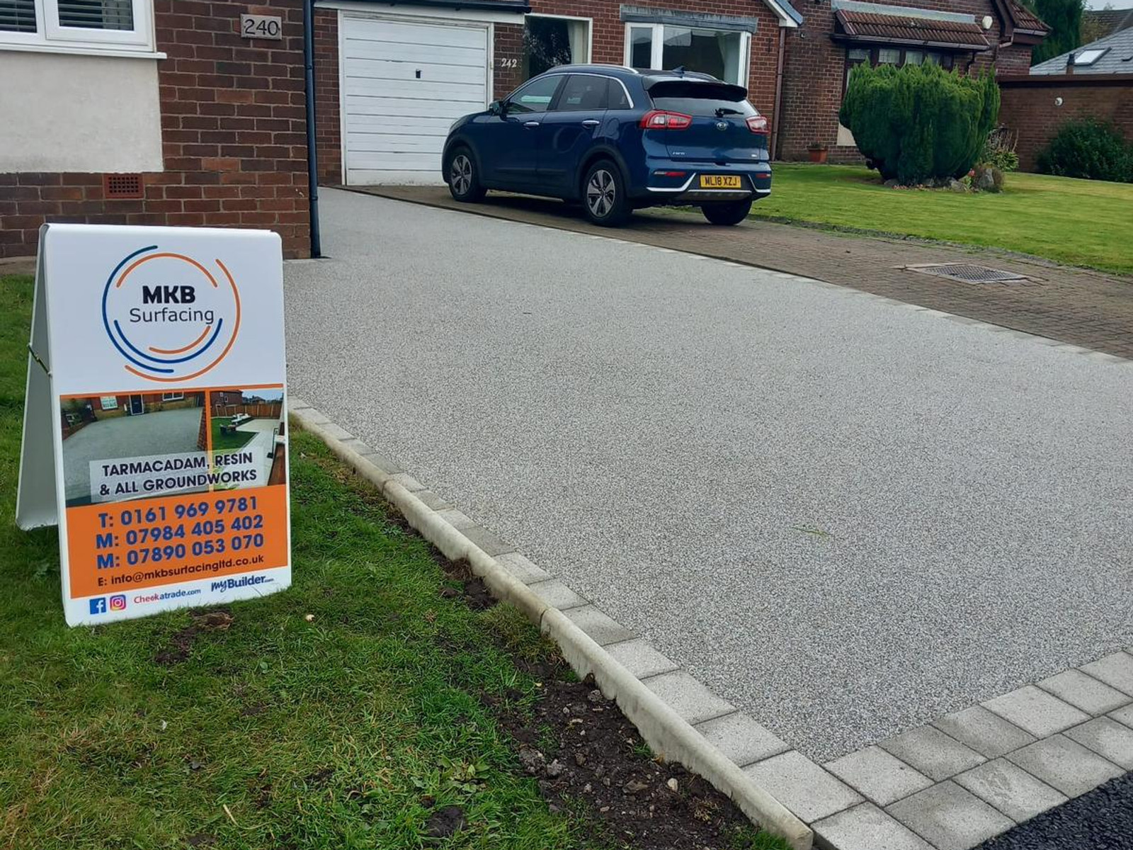 Light grey resin driveway with stone block border at a residential property