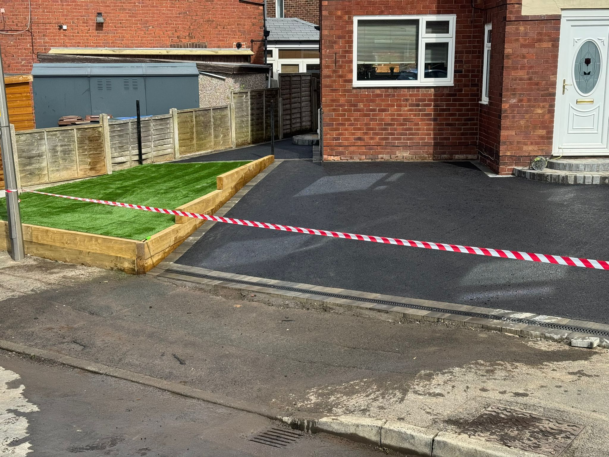 Tarmac driveway with artificial grass and caution tape (alternate angle)