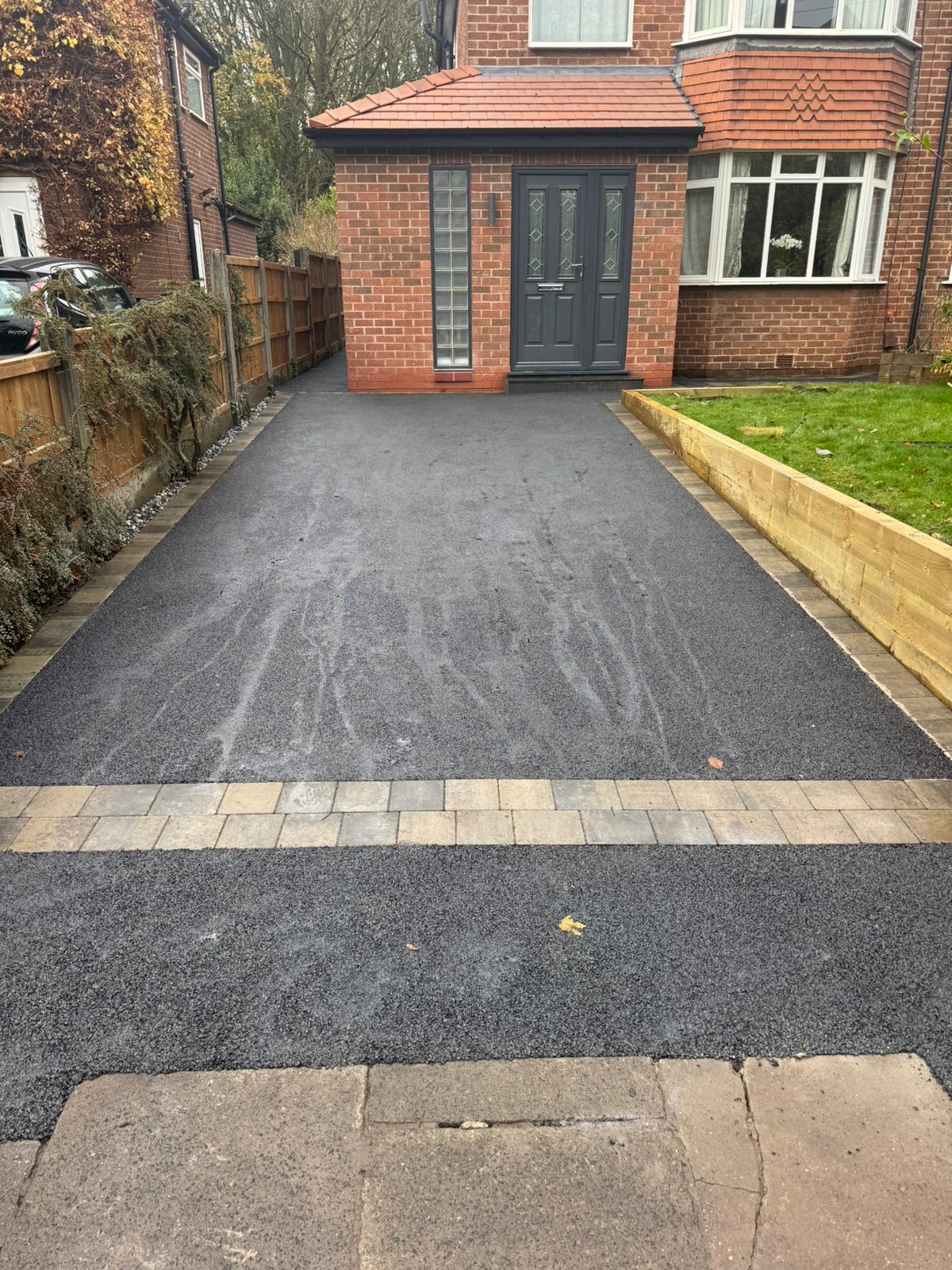 Long tarmac driveway with decorative block strip and sleeper retaining wall