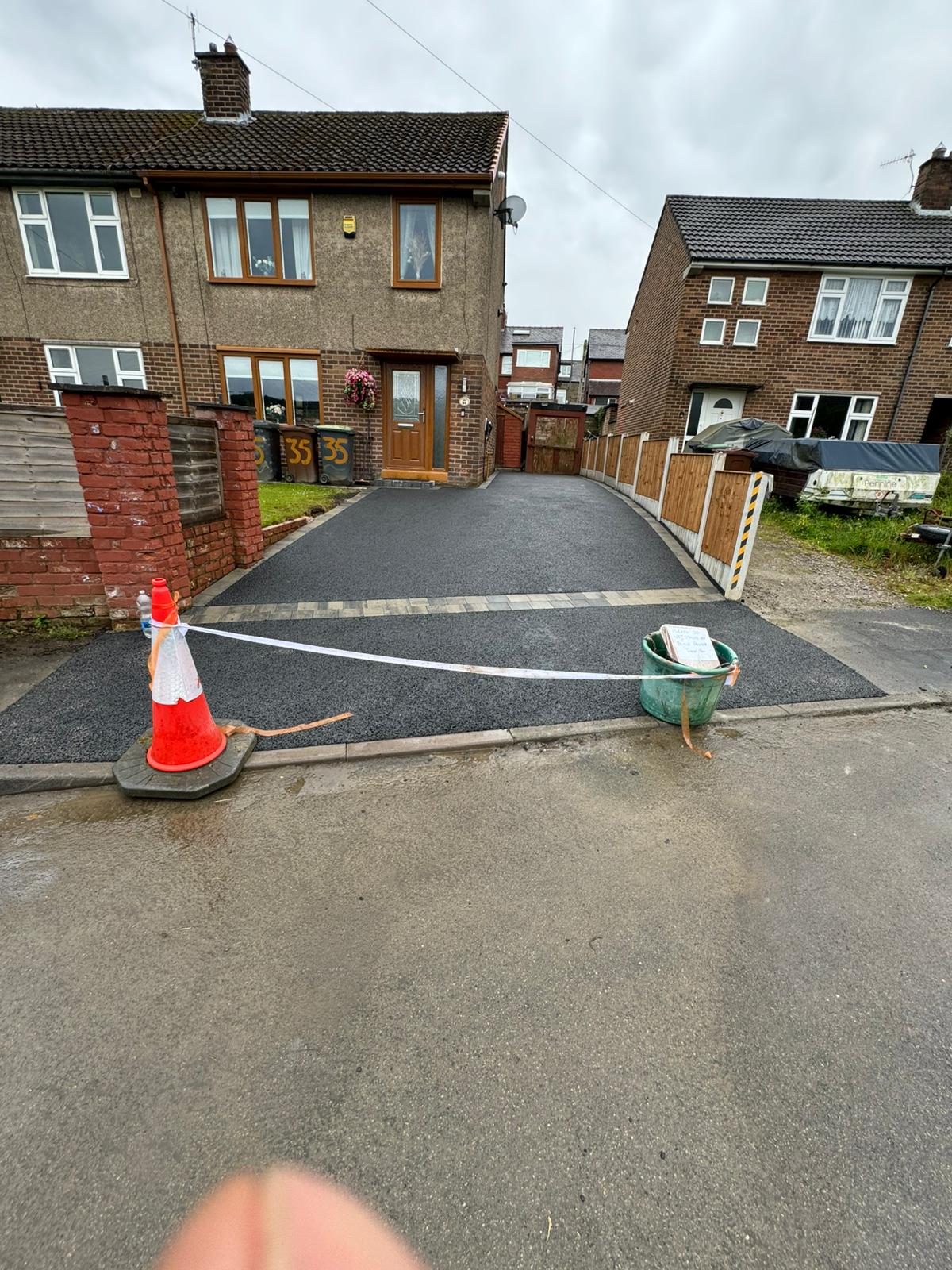 Fresh tarmac driveway with block strip, cone and caution tape at house 33