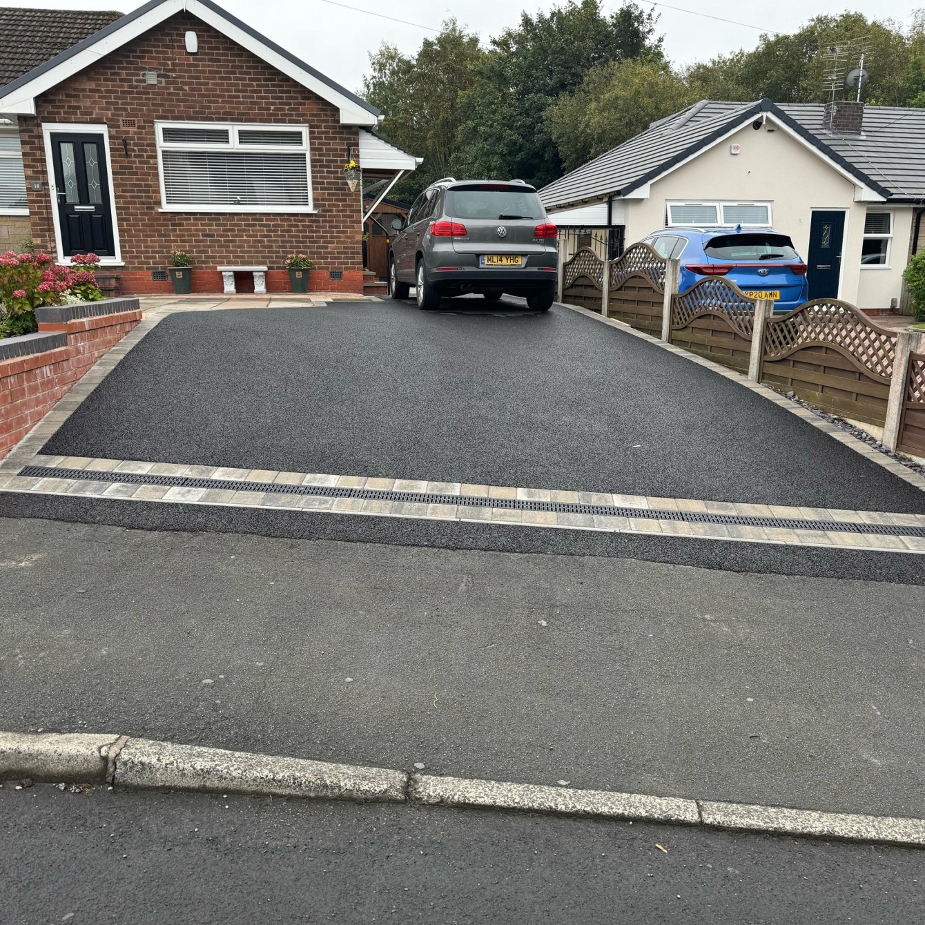 Sloping tarmac driveway with block drainage channel and light block border