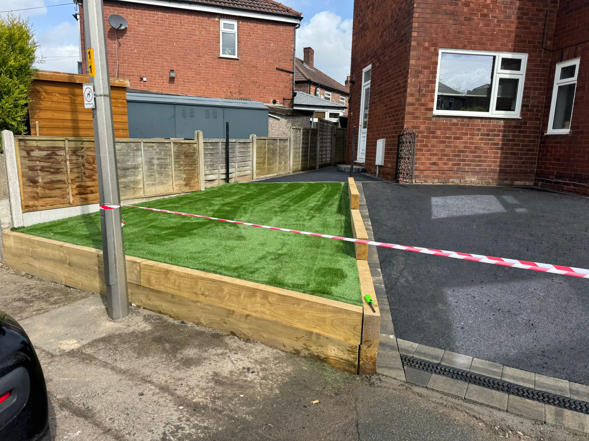 Fresh tarmac driveway with artificial grass/sleepers and caution tape (alternate high-res angle)
