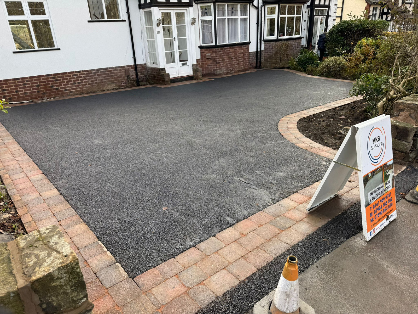 Newly laid tarmac driveway with brick paver border ready for use